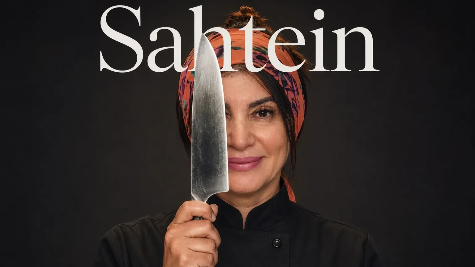 Chef Regina Maatouk segurando uma faca de cozinha diante do rosto, com lenço laranja, sobre fundo escuro
