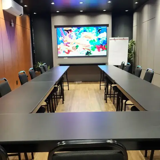 Sala montada em U para reunião com duas telas no Espaço Convivium Vila Olímpia